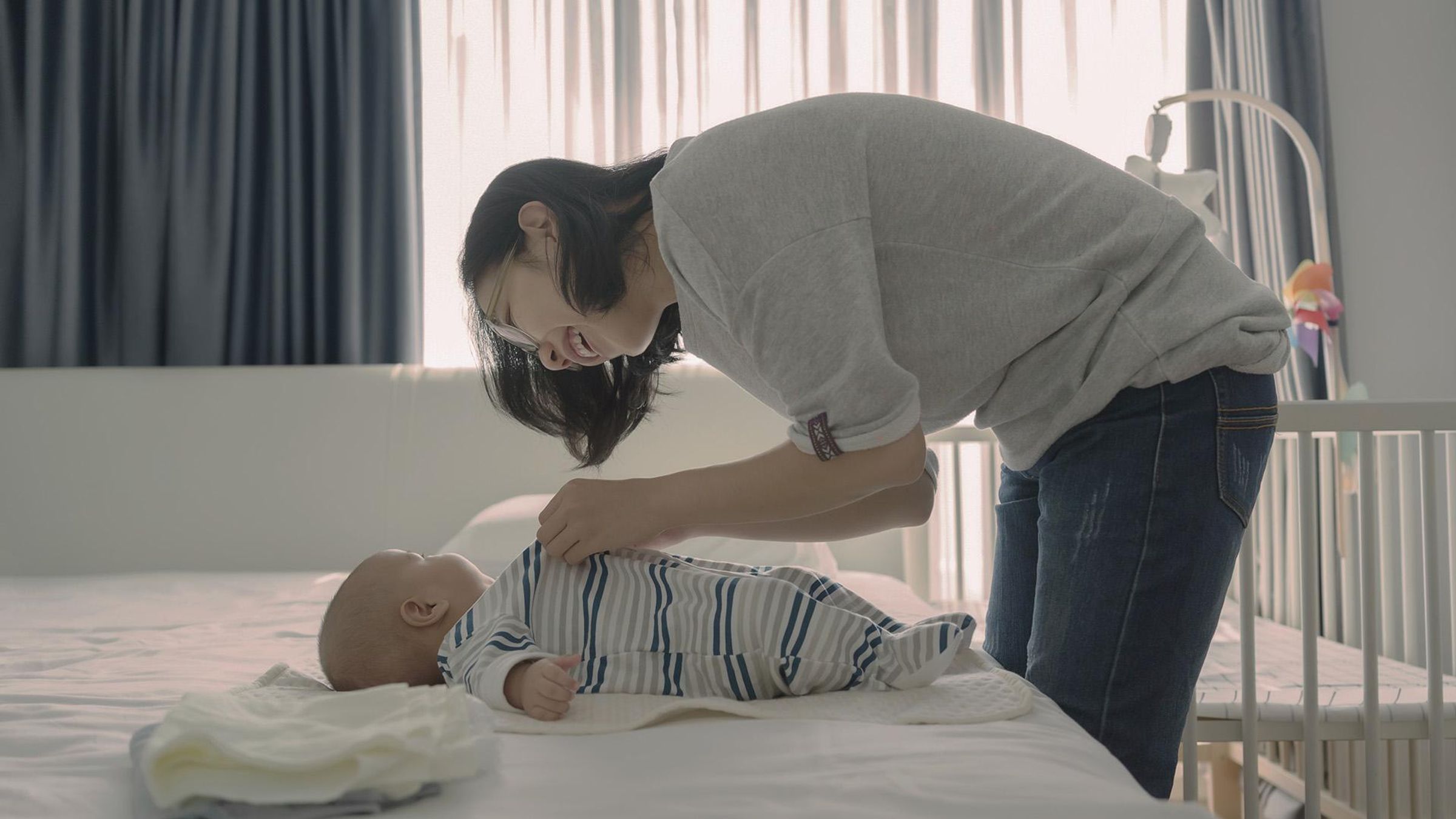 Mamá vistiendo a su bebé menor de 1 año