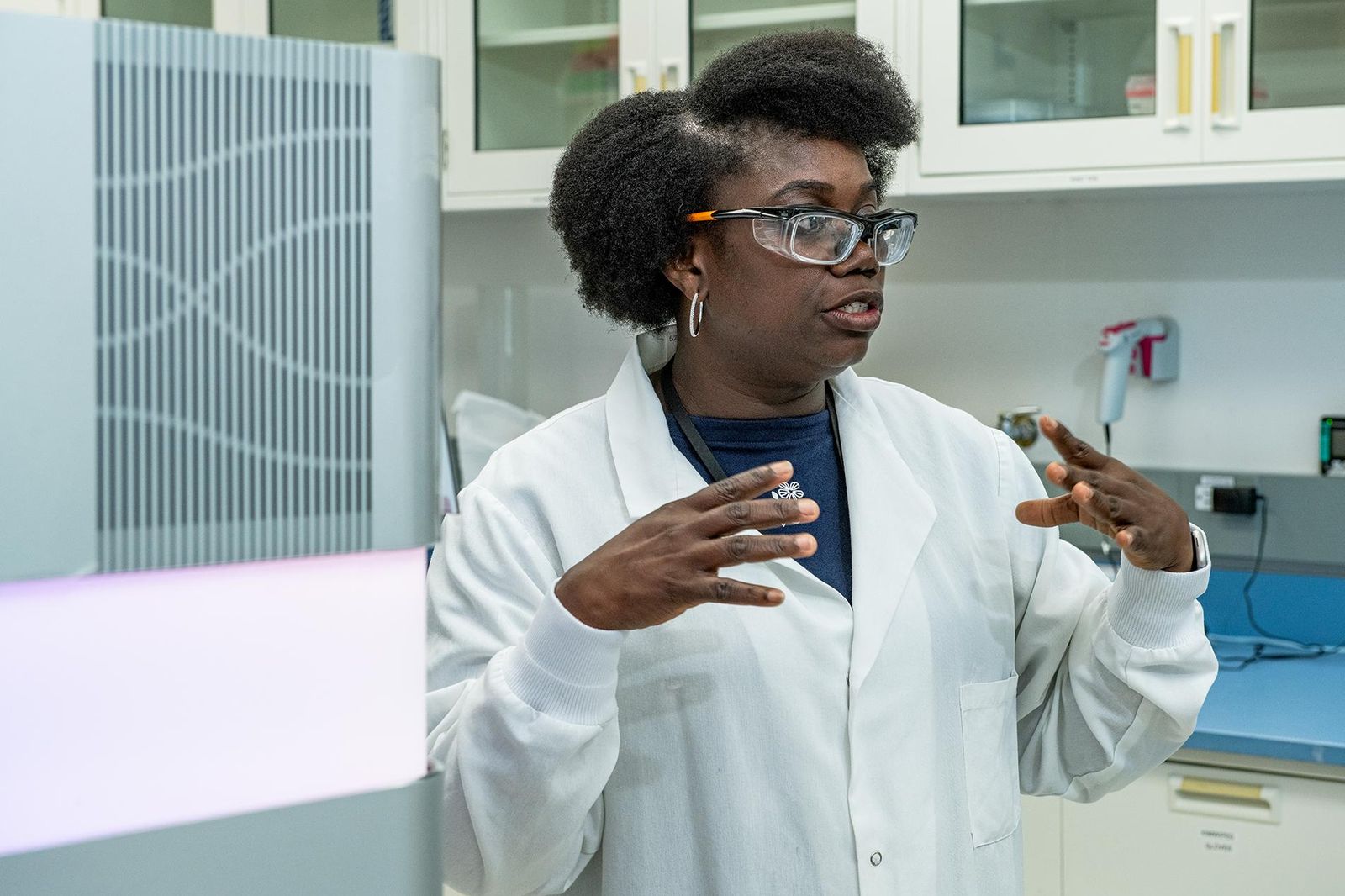 Francisca Aidoo-Nyarko, vêtue d'une blouse blanche, de lunettes de sécurité et de créoles, parle en faisant des gestes avec ses mains