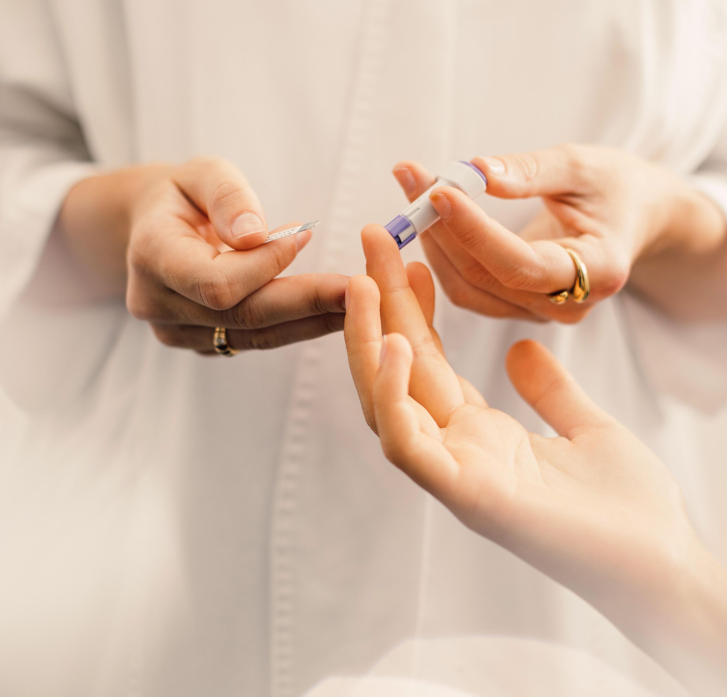Close-up of a hand receiving a finger prick for blood sugar measurement.