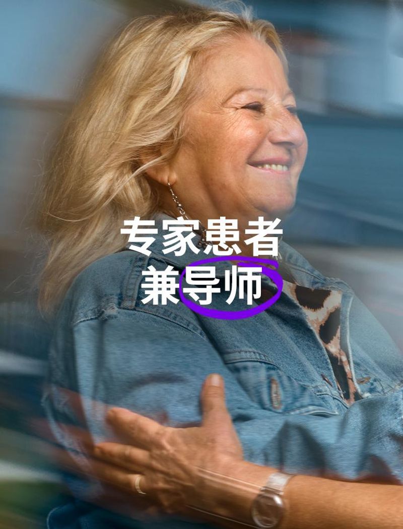 位穿着蓝色牛仔夹克的微笑女士伸出手臂,拥抱另一位戴眼镜的女士 叠加文字显示:“专家患者兼导师”