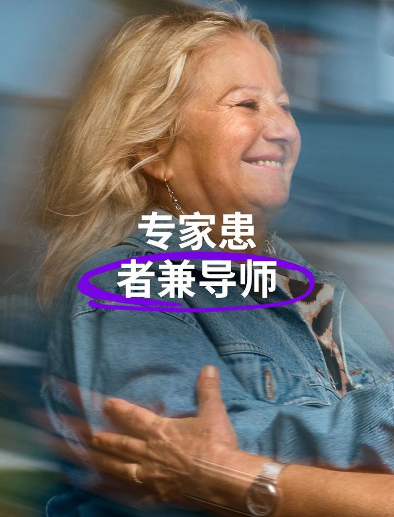 位穿着蓝色牛仔夹克的微笑女士伸出手臂,拥抱另一位戴眼镜的女士 叠加文字显示:“专家患者兼导师”