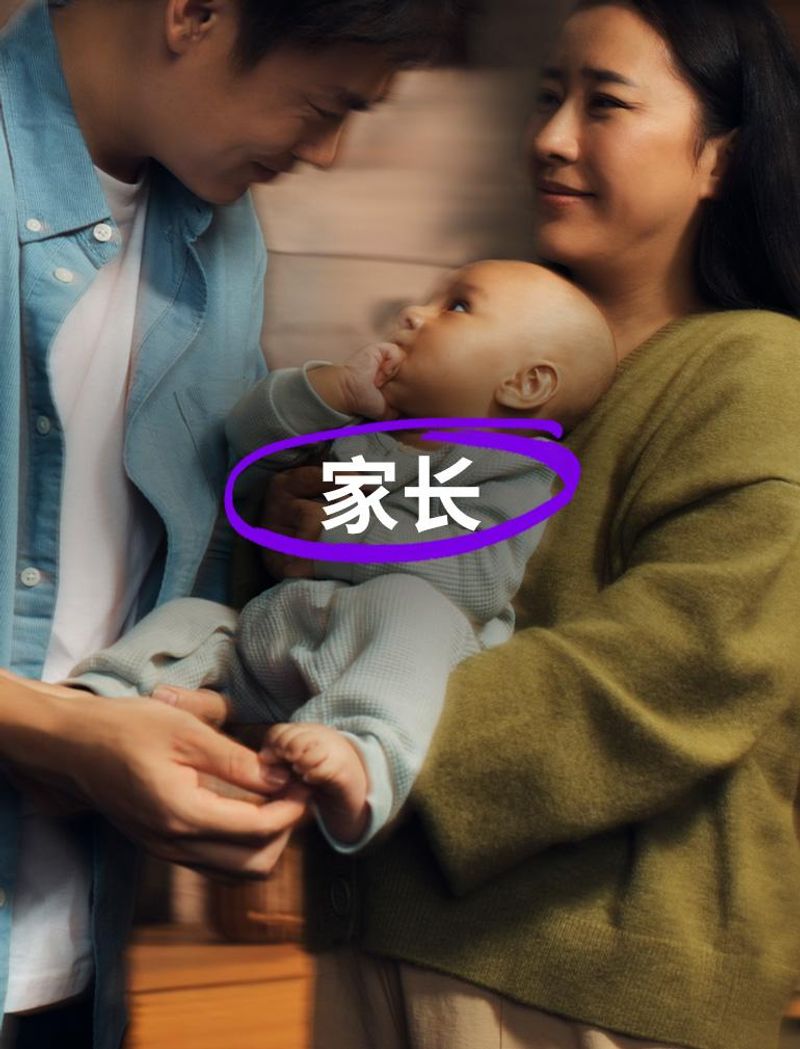 位穿蓝色衬衫的男士和一位穿绿色毛衣的女士共同抱着一个婴儿。婴儿的手放在嘴里,抬头看着那位男士。叠加文字显示:“家长”