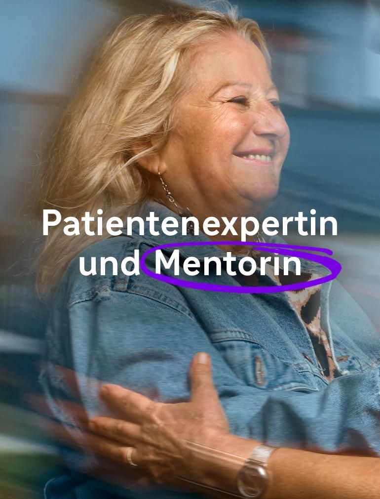 Eine lächelnde Frau in einer blauen Jeansjacke streckt die Hand aus, um eine andere Frau mit Brille zu umarmen. Überlagerter Text lautet: „Patientenexpertin und Mentorin“​