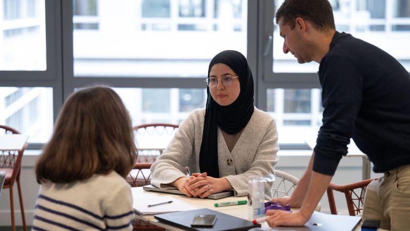 Un homme et une femme dans un bureau moderne, devant un écran d'ordinateur.
