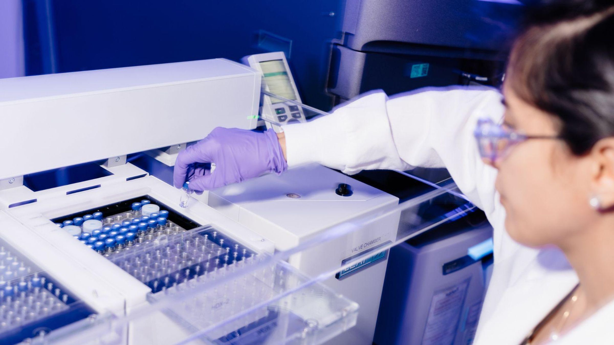 Banafsheh Mehrazma, Vaccines Technologist at Sanofi's Toronto Campus, working with laboratory equipment while wearing protective gear including lab coat and purple gloves