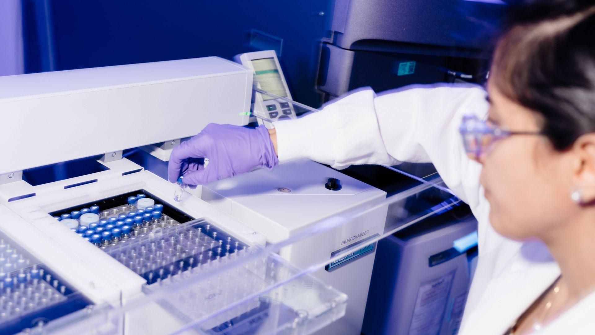 A technologist, wearing purple glove and safety glasses performing structural analysis by HDX-MS, handling samples with precision