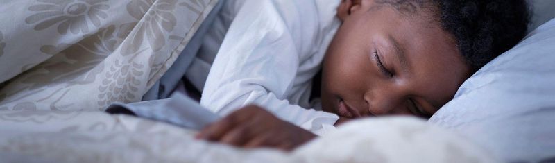 Plan serré sur un enfant dormant paisiblement dans un lit