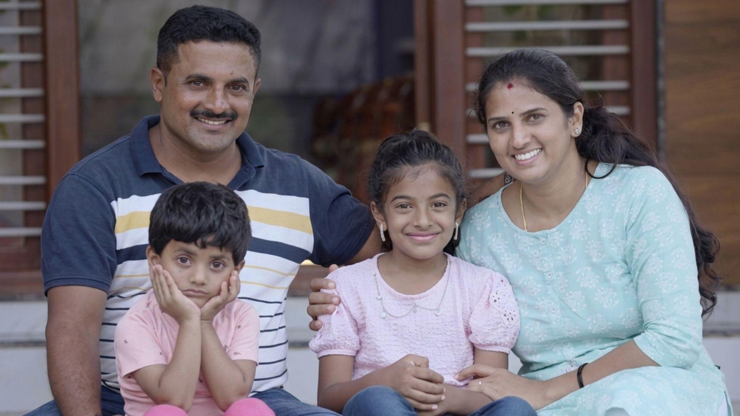 A photo of Khushika, who has ASMD, sitting with her family.