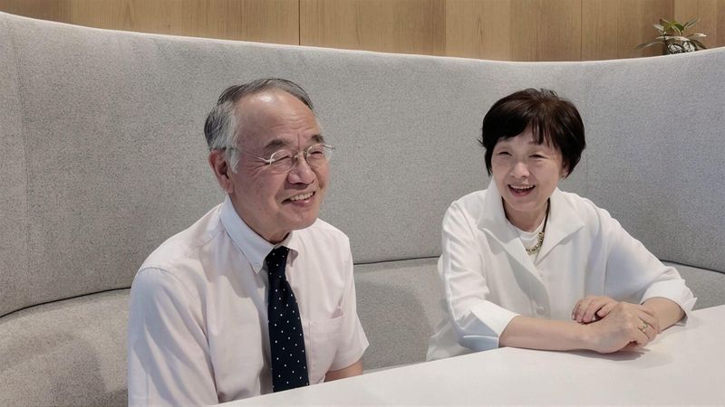 Man and woman sit side-by-side at a table, smiling