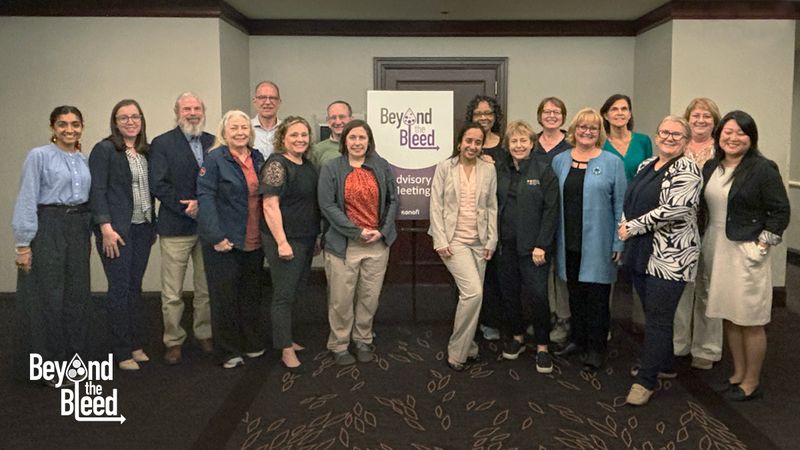 Group photo of Sanofi’s Beyond the Bleed professional advisory board standing with a Beyond the Bleed sign