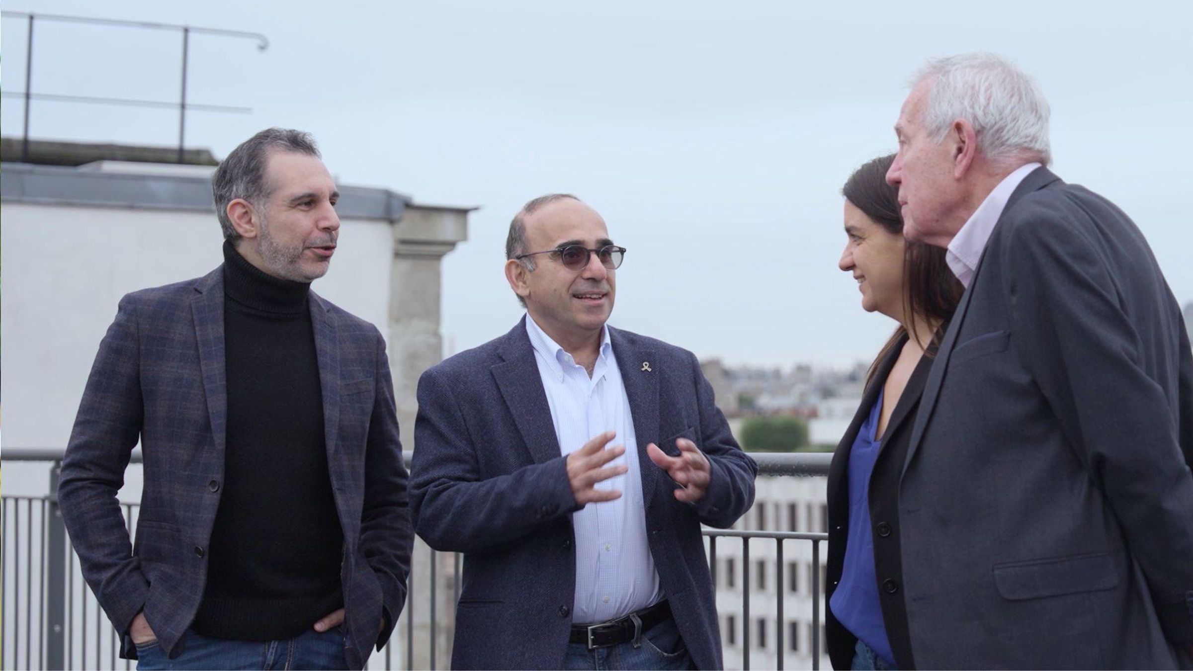 Four business professionals having a discussion on an outdoor rooftop terrace