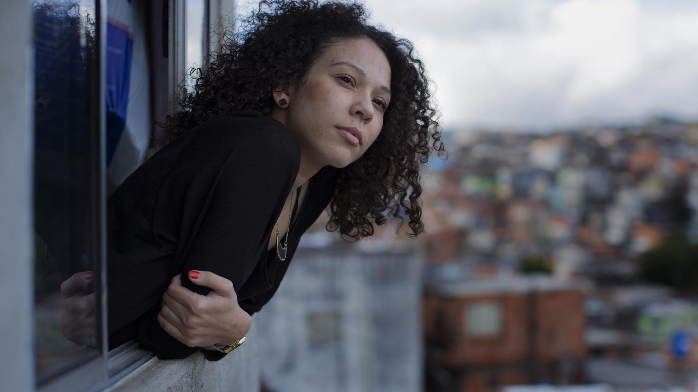 A woman leans out of her apartment window in Brazil 