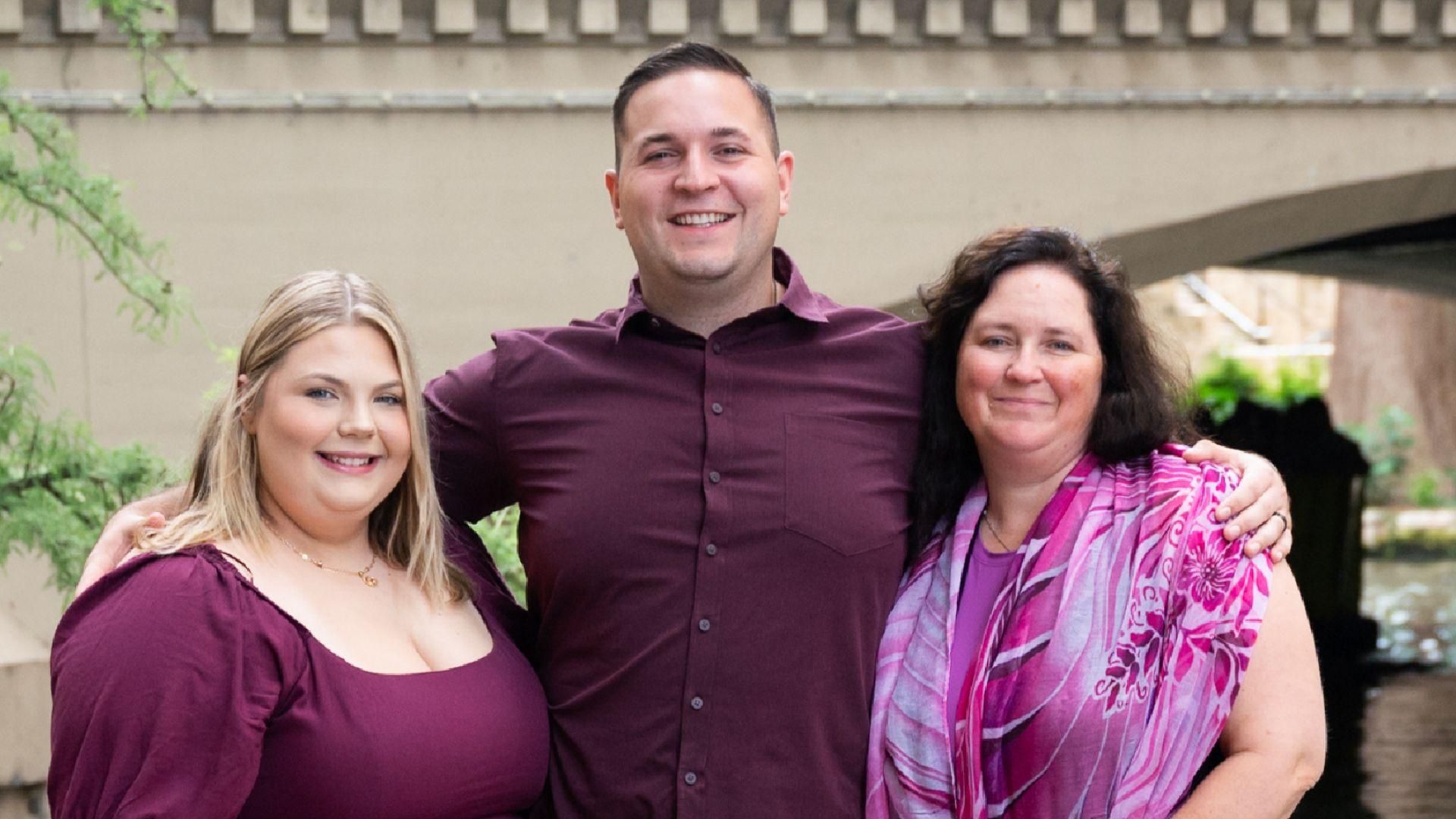 John se tient debout avec son épouse et sa mère