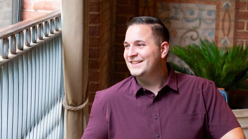 John, assis sur une chaise, regarde au loin et sourit